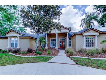 Charming single-story home featuring a well-manicured lawn, mature landscaping, and inviting column-supported front porch at 15302 Lake Maurine Dr, Odessa, FL 33556