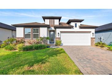 Charming single-Gathering home featuring a well-manicured lawn, a two-car garage and stone accents at 34266 Radley Way, Wesley Chapel, FL 33545