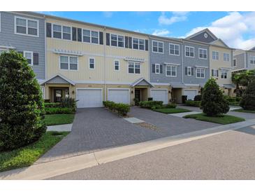 Townhomes with varied colors offer garages, tasteful landscaping and brick paver driveways under a blue sky at 4139 Rocky Shores Dr, Tampa, FL 33634