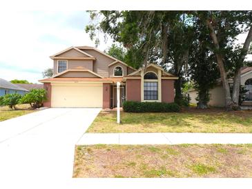 Charming two-story home features a brick facade and a two-car garage with lush front lawn at 4214 Longfellow Dr, Plant City, FL 33566