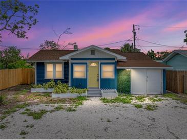 Charming blue home with a yellow door, lush greenery, and a spacious gravel driveway at 4727 17Th S Ave, St Petersburg, FL 33711