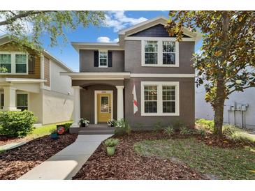 Charming two-story home featuring a bright yellow front door, manicured landscaping, and a welcoming walkway at 5914 Goldenbark Pl, Lithia, FL 33547