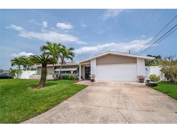 Charming single-story home featuring a two-car garage, lush lawn, and mature palm trees at 7851 120Th St, Seminole, FL 33772