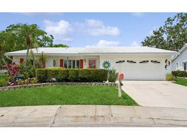 Charming single-story home featuring a well-manicured lawn, vibrant flowers, and a two-car garage at 9018 39Th N Ln # 5, Pinellas Park, FL 33782