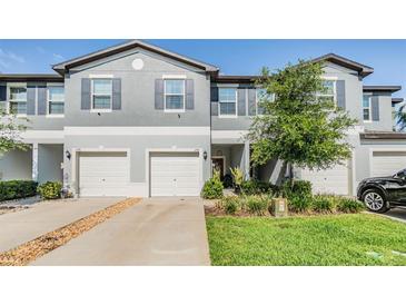 Charming townhome featuring a gray exterior, white garage doors, and well-maintained landscaping at 1594 Cassius St, Lutz, FL 33549