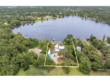 Stunning aerial view of lakeside property with lush landscaping and private dock on a clear blue lake at 13533 Bay Lake Ln, Tampa, FL 33618