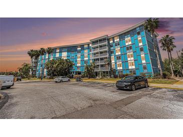 Bright blue condo building with ample parking and lush palm trees, offering a vibrant living space at 3315 58Th S Ave # 605, St Petersburg, FL 33712