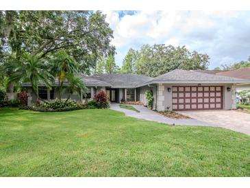Charming single-story home with well-manicured lawn, mature trees, and an attached two-car garage at 3428 Valley Ranch Dr, Lutz, FL 33548