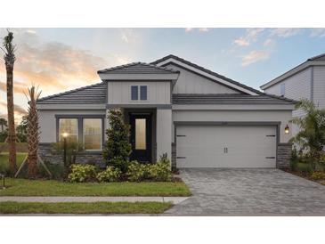 Charming single-Gathering home featuring a well-manicured lawn, stone accents, and a two-car garage at 3818 Farm Garden Ct, Lakewood Ranch, FL 34211