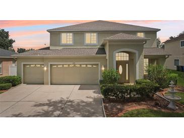 Charming two-story home featuring a three car garage, well-maintained landscaping, and a classic entryway with a decorative door at 4224 Fleewell Ct, Valrico, FL 33596