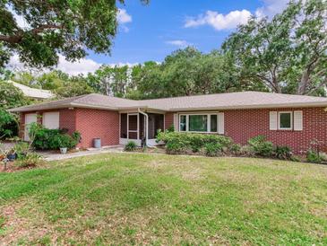 Well-manicured front yard of a cozy brick home, enhanced by vibrant green grass at 7216 N Mobley Rd, Odessa, FL 33556