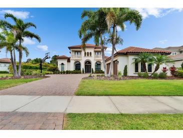Stately two-story home featuring a red tile roof, balconies, and a lushly landscaped yard with mature palm trees at 16406 Chapman Crossing Dr, Lithia, FL 33547