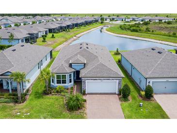 Waterfront home featuring a two-car garage, well-maintained landscaping, and a brick paved driveway at 19877 Sea Glass Cir, Land O Lakes, FL 34638