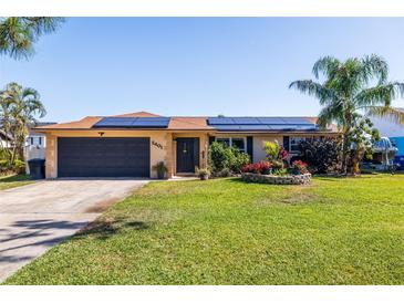 Charming single-story home featuring a well-manicured lawn, solar panels, and a two-car garage at 2401 66Th S Ave, St Petersburg, FL 33712