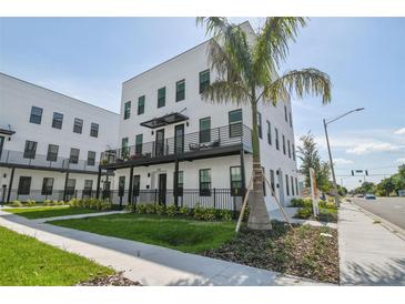 Modern, multi-story building with black balconies, lush landscaping, and a tall palm tree on a clear, sunny day at 2758 5Th S Ave, St Petersburg, FL 33712