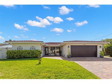 Charming single-story home with a red tile roof, a lush green lawn, and a brick driveway at 4425 13Th Ne Way, St Petersburg, FL 33703