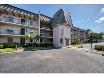 Condo building featuring neutral stucco, black iron railings, and mature landscaping creating a welcoming curb appeal at 712 Cordova Greens # 712, Largo, FL 33777
