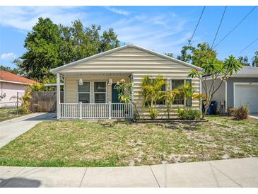 Charming single-story home with light beige siding, a well-manicured lawn, and a cute white picket fence at 2604 E Chelsea St, Tampa, FL 33610