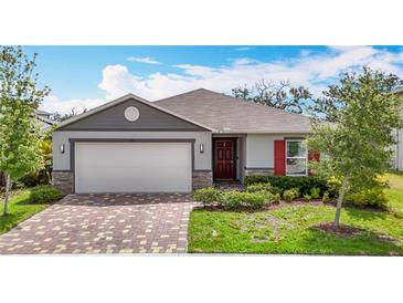 Charming single-story home boasts a two-car garage, brick paver driveway, manicured landscaping, and colorful accents at 3891 Reflection Dock Dr, Seffner, FL 33584