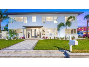 Beautiful two-story home with well-manicured lawn, tropical plants and tiled entryway at 650 70Th Ave, St Pete Beach, FL 33706