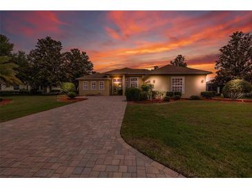 Beautiful single-story home with brick-paved driveway and manicured landscaping under a vibrant sunset sky at 8308 Mobile Cir, Weeki Wachee, FL 34613