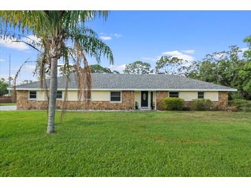 Charming single-story home featuring a lush green lawn and a stone and siding exterior at 903 Tomahawk Trl, Brandon, FL 33511