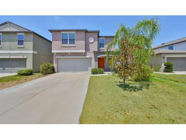 Charming two-story home with a well-manicured lawn, a two-car garage, and an orange front door at 10210 White Linen Ave, Riverview, FL 33578