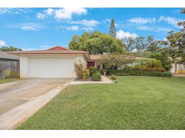 Charming single-story home featuring a well-manicured lawn, two-car garage and vibrant landscaping at 13563 Cordova Dr, Largo, FL 33774