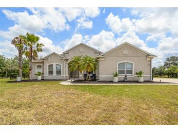 Charming home featuring lush landscaping, a well-maintained lawn, and mature palm trees at 2214 132Nd E Pl, Parrish, FL 34219