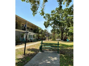 Charming condo with a lush green lawn and bench seating area for relaxing outdoors at 4051 58Th N St # 241C, Kenneth City, FL 33709