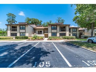 A condominium with two stories, a parking lot, sidewalks and green space at 105 Woodlake Wynde, Oldsmar, FL 34677