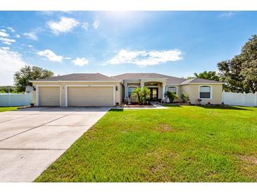 Traditional home with a three-car garage, large lawn, mature landscaping, and neutral color scheme at 1521 Avondale Ridge Dr, Plant City, FL 33567