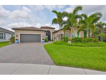 Charming home with a manicured lawn, colorful flowerbeds, paver driveway, and a two car garage at 15303 Valencia Del Sol St, Wimauma, FL 33598