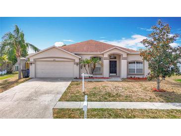 Charming single-story home with a well-manicured lawn, mature trees, and a two-car garage at 19910 Wyndmill Cir, Odessa, FL 33556