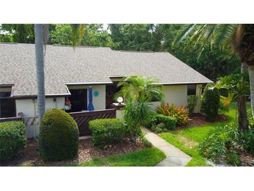 Inviting single-story home featuring a well-manicured lawn, vibrant landscaping, and a charming front entrance at 2913 Fig Ct, Palm Harbor, FL 34684