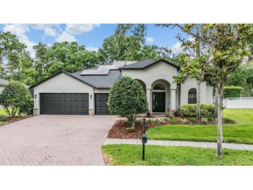 Charming single-story home features a brick driveway, a manicured lawn, and a three-car garage at 5109 Hartwell Loop, Land O Lakes, FL 34638