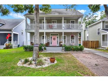 Charming two-story home with a welcoming front porch, second-story balcony, pink door, and landscaped yard at 5907 S Elkins Ave, Tampa, FL 33611