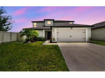 Charming two-story home showcasing a well-manicured lawn, two-car garage, and neutral color scheme at 1009 Wynnmere Walk Ave, Ruskin, FL 33570