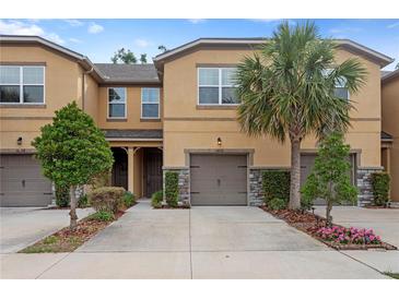 Inviting townhome showcasing stucco facade, well-manicured landscaping, and a private single-car garage at 14110 Damselfly Dr, Tampa, FL 33625