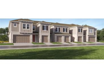 New townhome construction with individual garages and modern facade, complemented by a green lawn at 3473 Lapis Lake Dr, Zephyrhills, FL 33541
