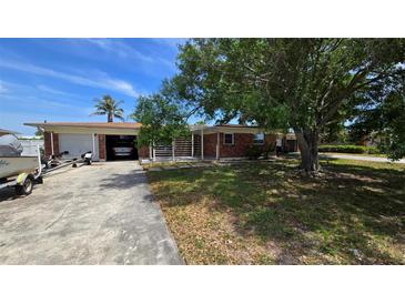 Charming one-story home featuring a brick facade, garage, and mature trees enhancing curb appeal at 3925 W Eden Roc Cir, Tampa, FL 33634