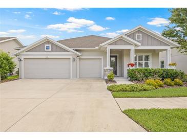 Charming one-story home featuring a three-car garage and beautifully landscaped front yard with colorful flowers at 4166 Epic Cv, Land O Lakes, FL 34638