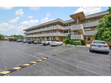Exterior view of condo building with parking area, lush landscaping, and beautiful sunny skies at 5095 Bay Ne St # 210, St Petersburg, FL 33703