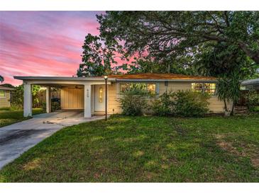 Charming single-story home with a covered carport and a lush front lawn at sunset at 629 Lexington St, Dunedin, FL 34698