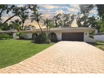 Charming home with a paver driveway, attached garage, and lush tropical landscaping at 8740 15Th N St, St Petersburg, FL 33702