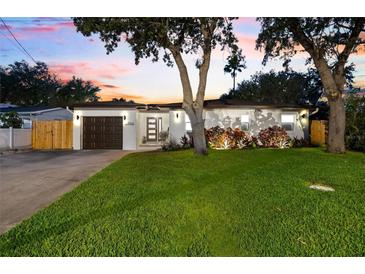 Charming home featuring a well-manicured lawn, stylish lighting, and a welcoming front entrance at 8848 Sunlit Cove Ne Dr, St Petersburg, FL 33702