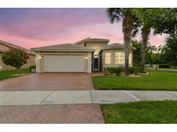 Inviting single Gathering home featuring a brick driveway, attached garage, and beautifully landscaped front yard at 16101 Cape Coral Dr, Wimauma, FL 33598