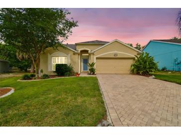Charming single-story home featuring a paved driveway, a well-manicured lawn, and mature landscaping at 1758 Biarritz Cir, Tarpon Springs, FL 34689