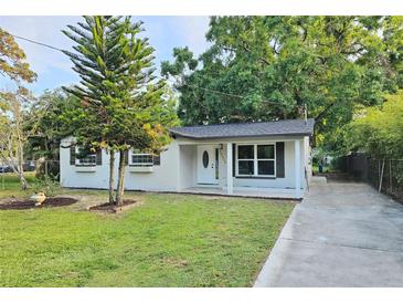 Charming home featuring a well-maintained front yard, fresh exterior paint and updated windows with decorative shutters at 10006 Memorial Hwy, Tampa, FL 33615