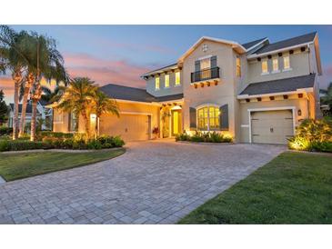 Elegant two-story home with a paver driveway, lush landscaping, and a welcoming entrance at dusk at 11327 Lake Lucaya Dr, Riverview, FL 33579